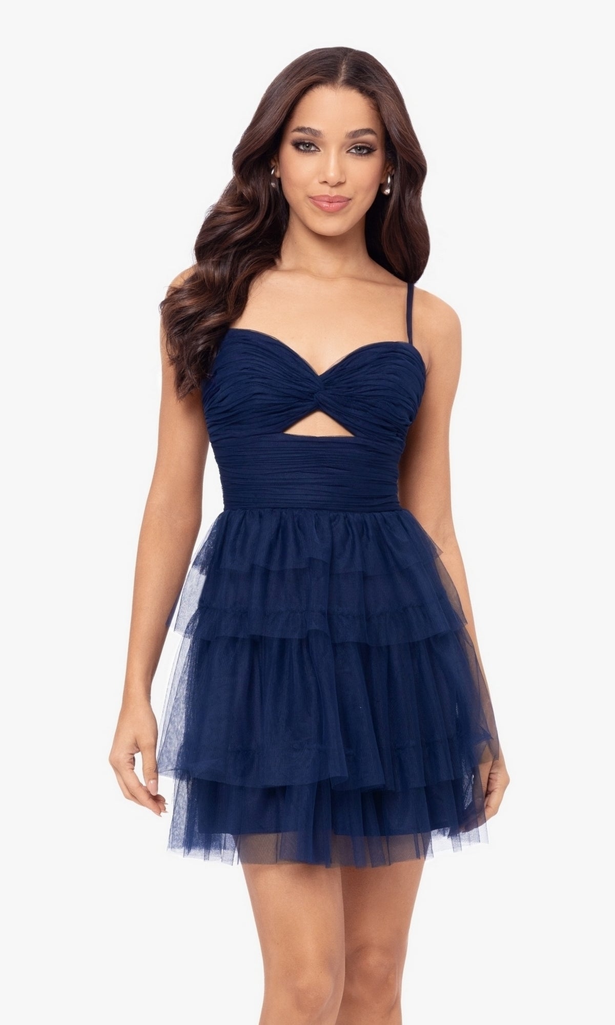 A woman wears the Cut-Out Short Ruffled Homecoming Dress 5098BN, featuring a navy junior party style with spaghetti straps, ruched sweetheart bodice, front cutout, and sleeveless tiered tulle ruffled A-line skirt against a white background.